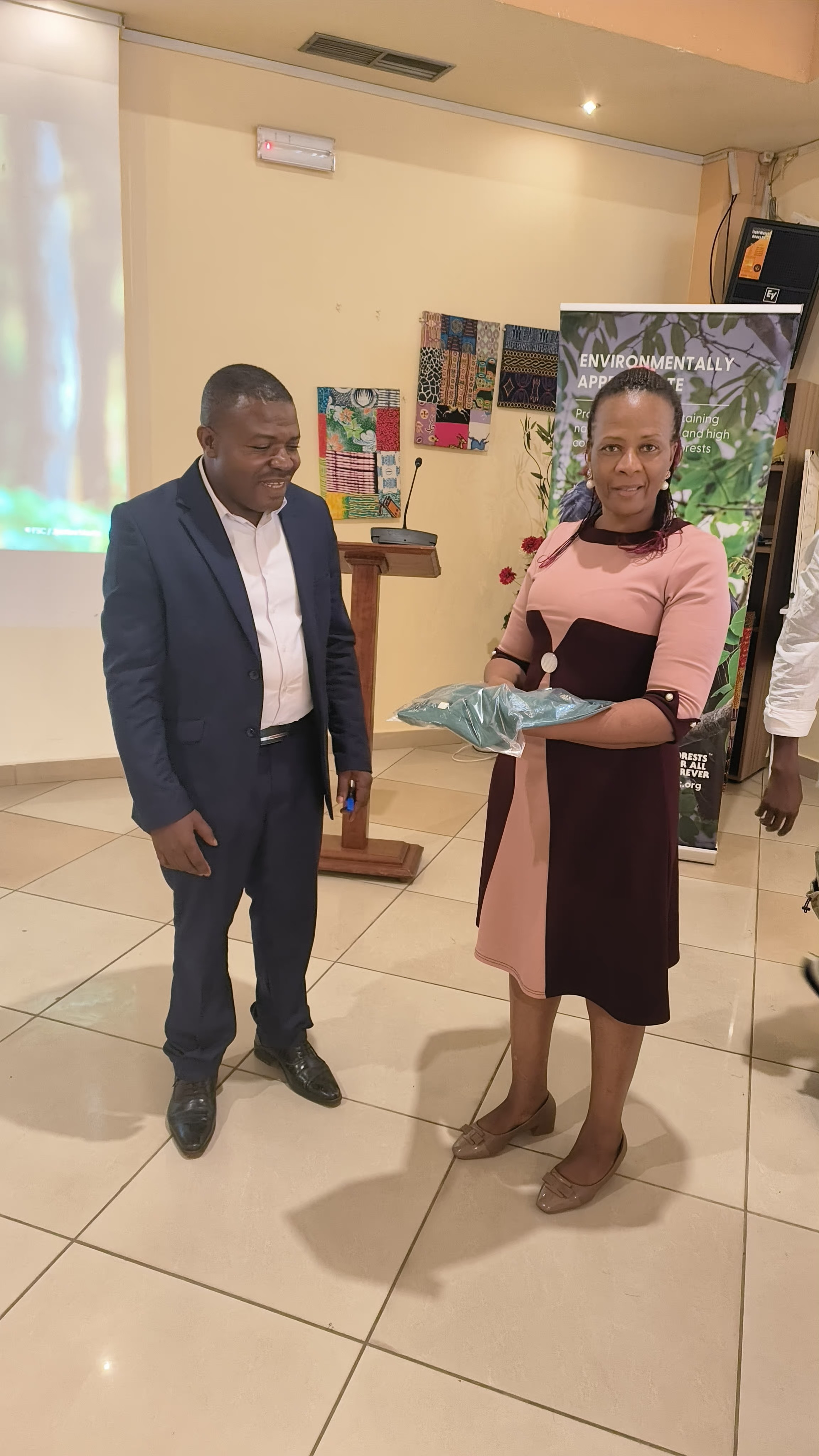 Annah Agasha, à gauche, remet un T-shirt du FSC à un membre du FSC à droite. Annah Agasha, Directrice adjointe du FSC Afrique (à droite) remet un T-shirt à un membre du FSC du Cameroun (à gauche).